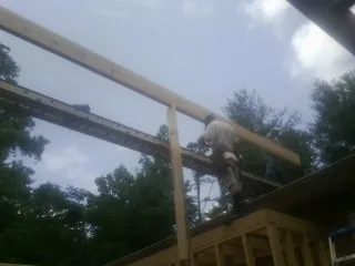 Carpenter setting a ridge beam over a new addition frame — Ice Dam Removal by Roofing Brothers in Castle Hayne