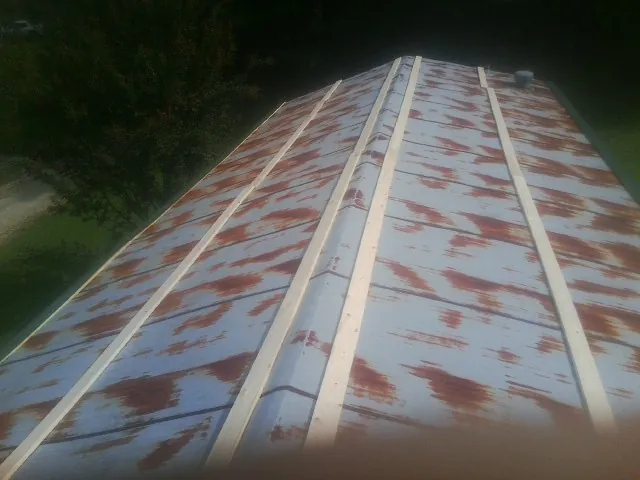 Rusted metal roof panels with new wood purlins before replacement — Storm Damage Roof Repair in Castle Hayne by Roofing Brothers
