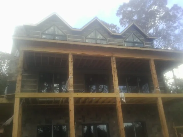 Dormers and porch framing on a large log home under construction — Roof Coating work by our crew in Castle Hayne