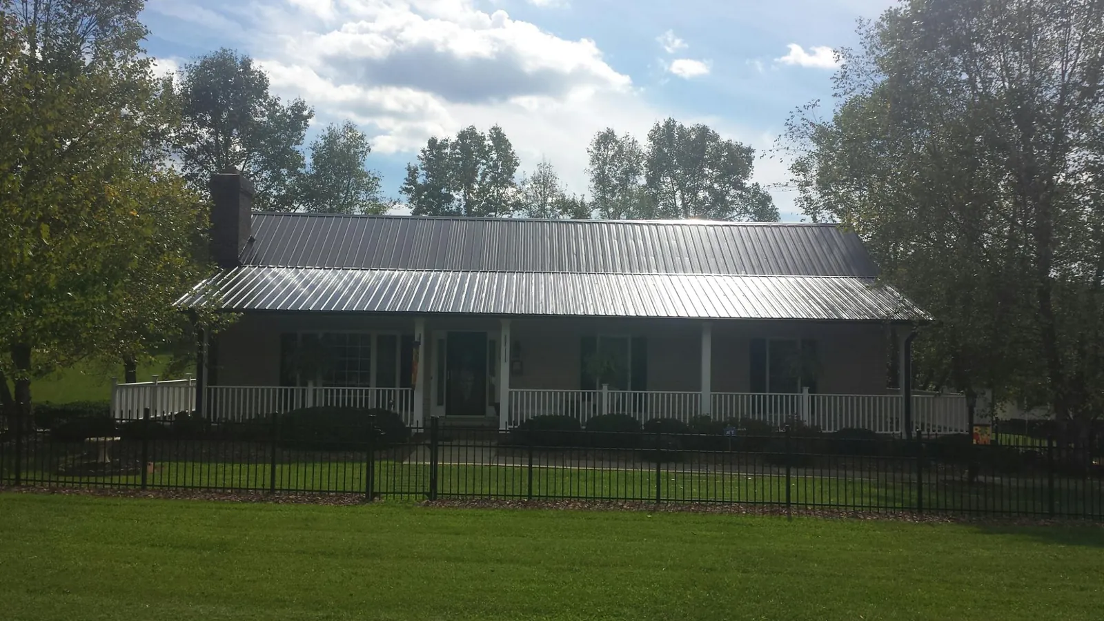 Gray metal roof on a brick ranch with a full width front porch — Gutter Guard Installation work by our crew in Castle Hayne