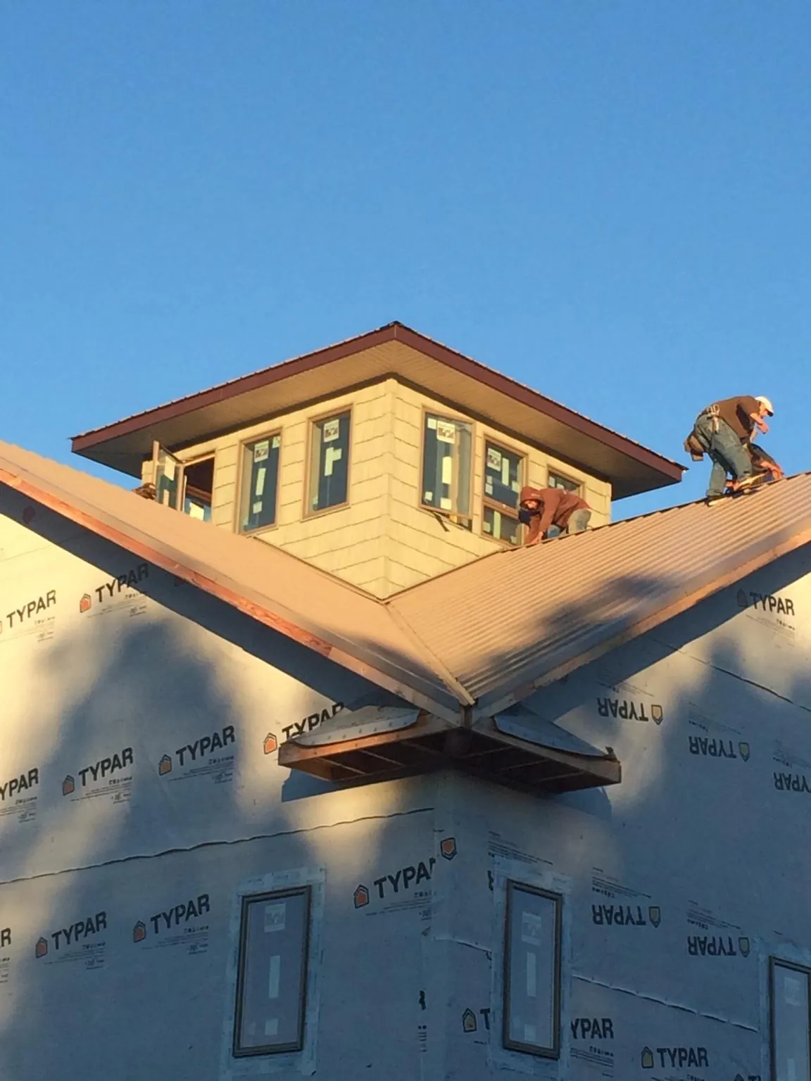 Roofers working around a rooftop cupola on a new metal roof at sunset — Roof Waterproofing in Castle Hayne by Roofing Brothers